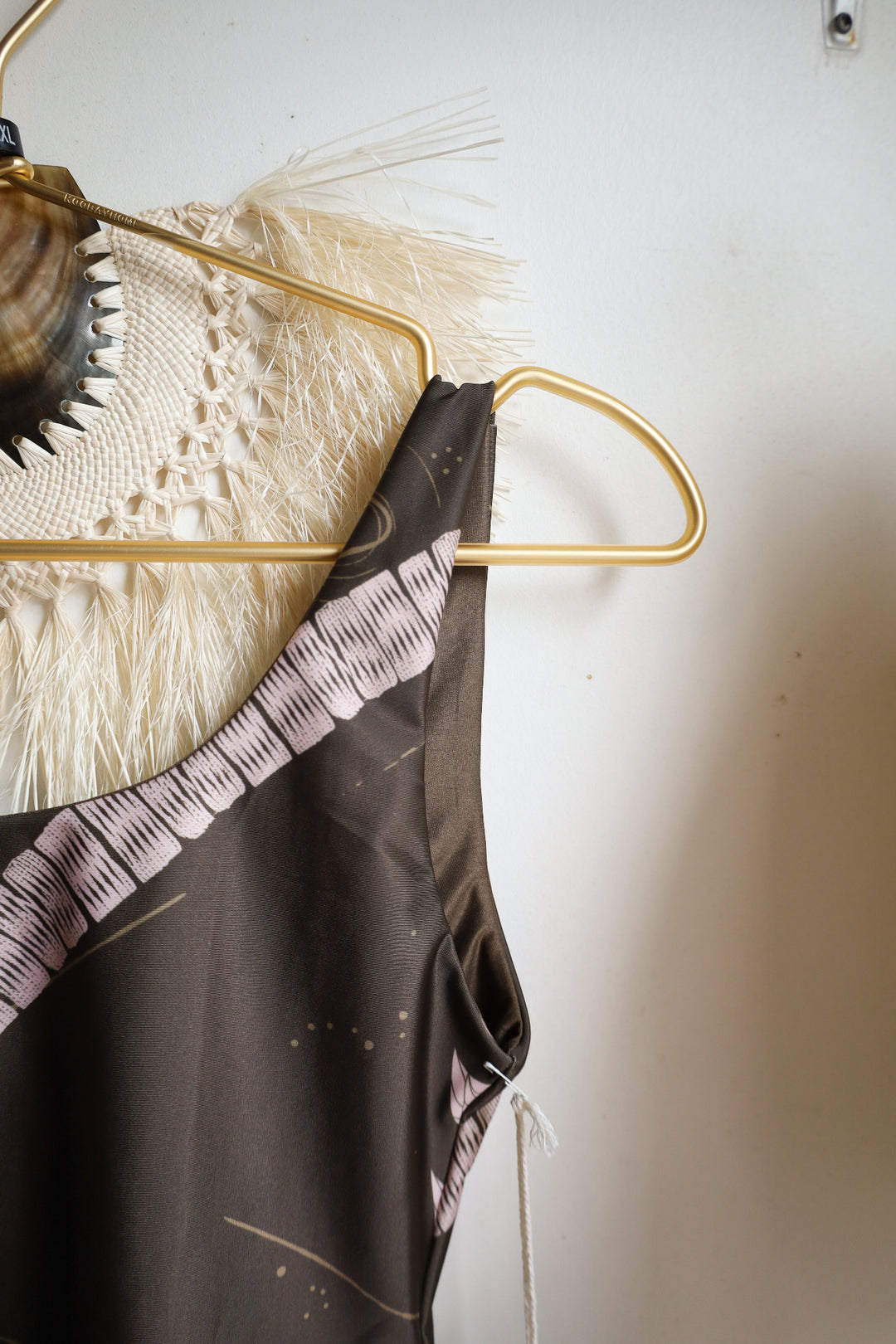 Gold hanger with a black garment against a white wall