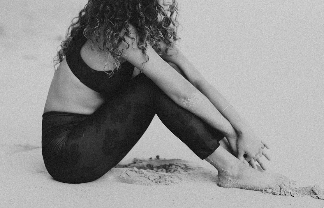 Person sitting on a sandy beach with a blurred background
